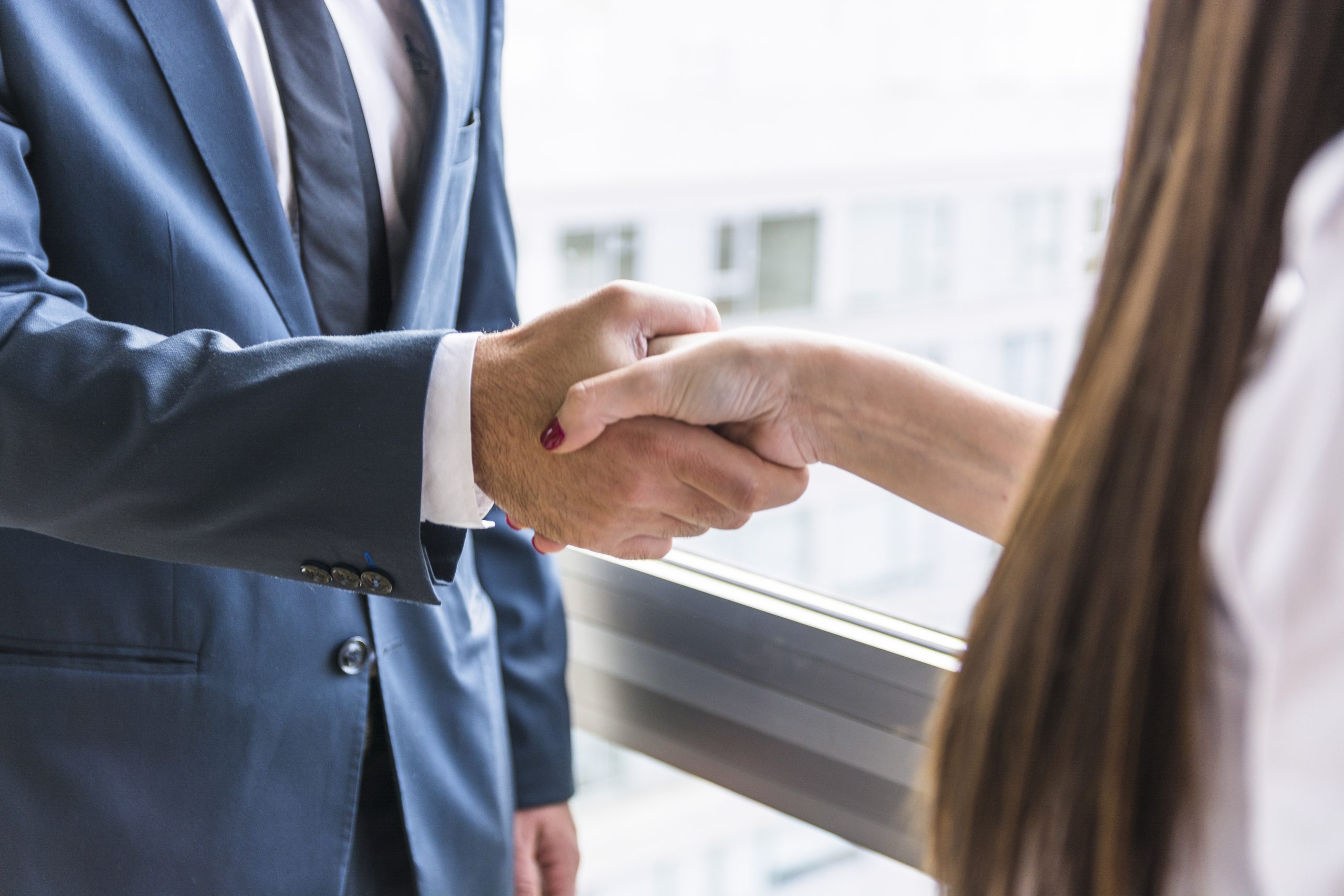 primer plano de la empresaria y empresario agitando las manos scaled